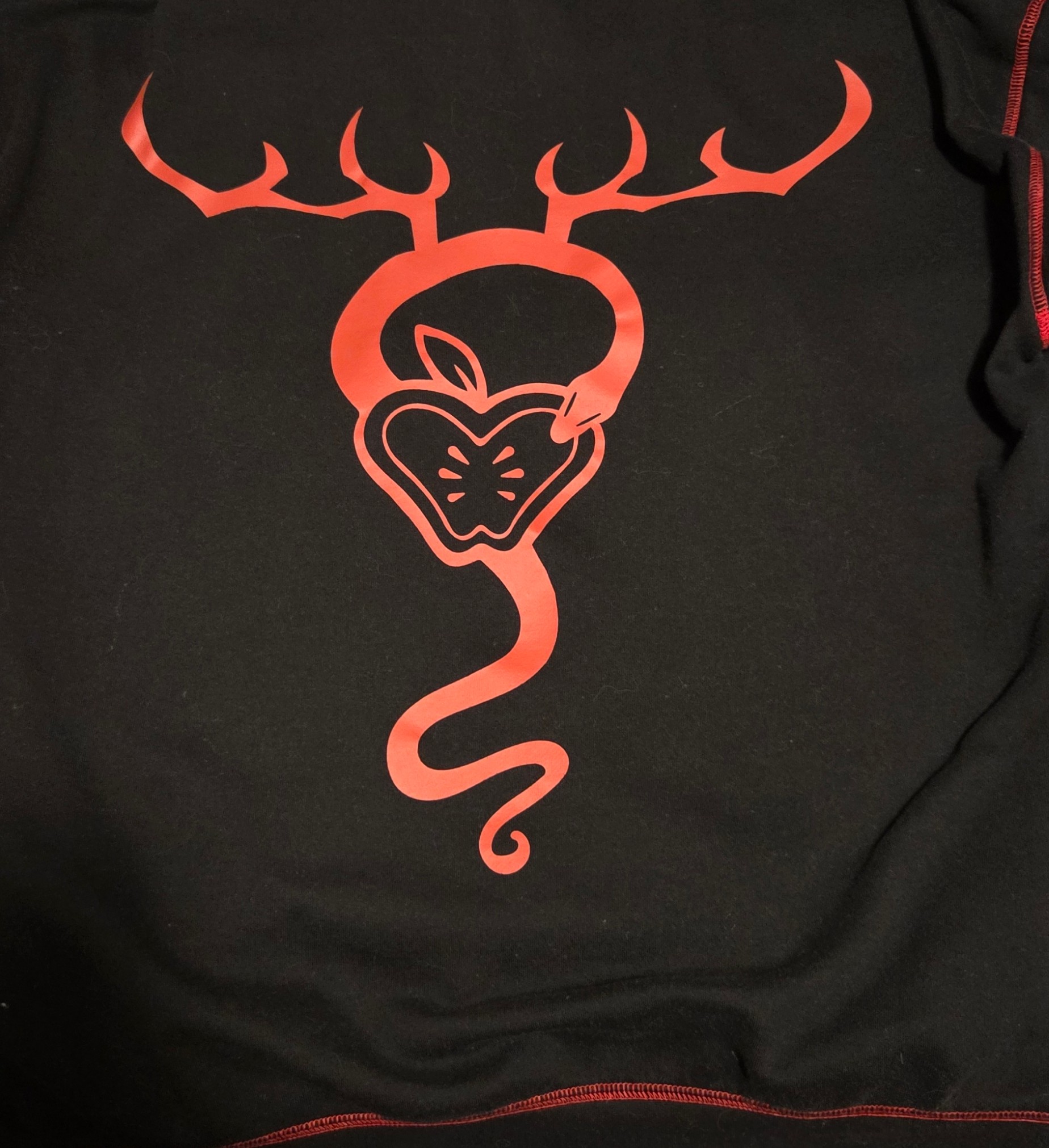 Back of hoodie from Hot Topic. In red, it depicts an apple, a snake curling around the apple, and antlers coming off the snake towards the top.